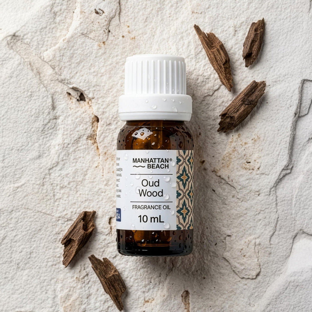 Bottle of Manhattan Beach Oud Wood fragrance oil on a textured stone surface with agarwood pieces.