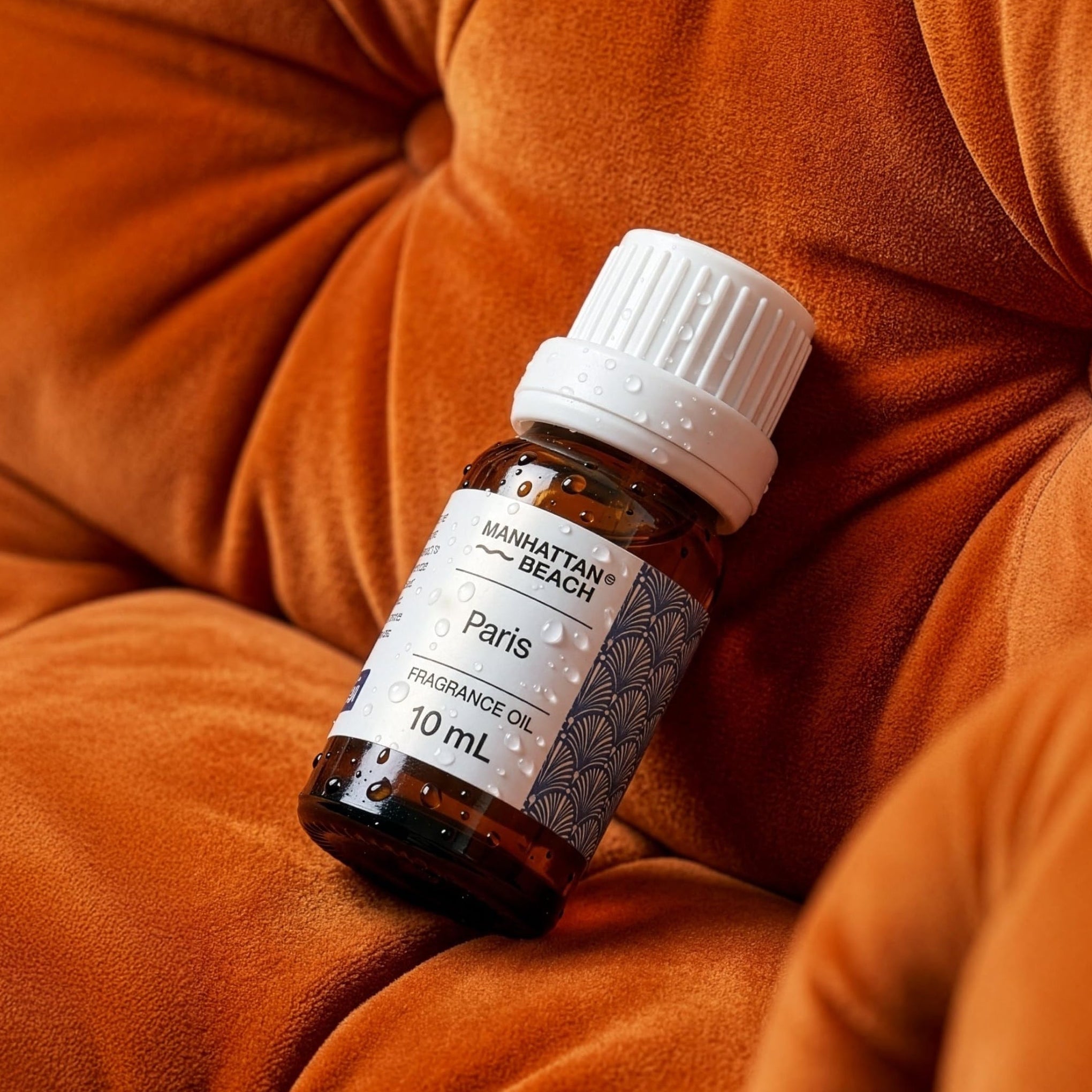 Small brown bottle with a white cap on an orange sofa