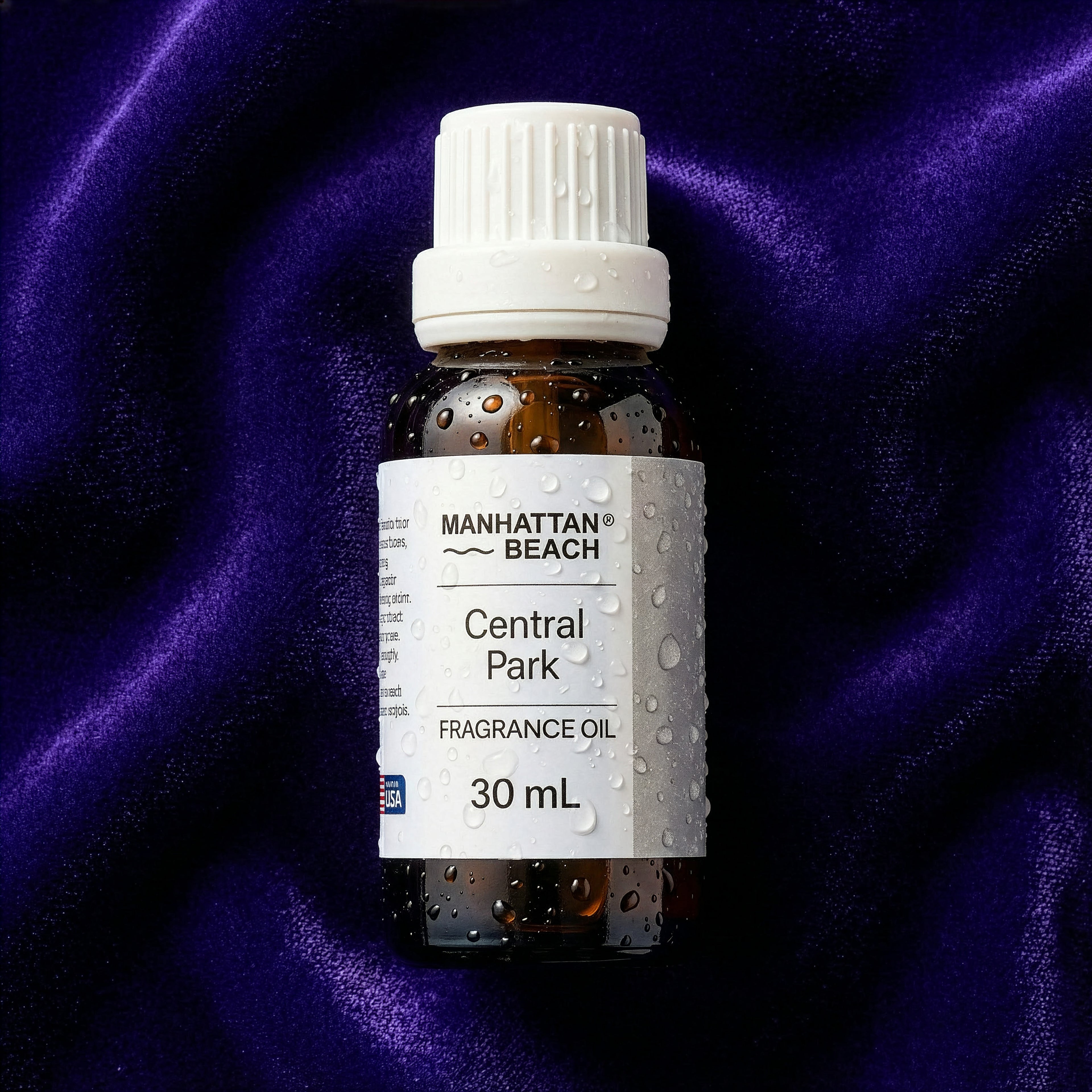 Bottle of Manhattan Beach Central Park fragrance oil on a purple fabric background