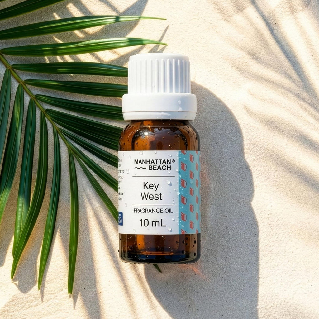 Bottle of Key West fragrance oil on sand with a palm leaf
