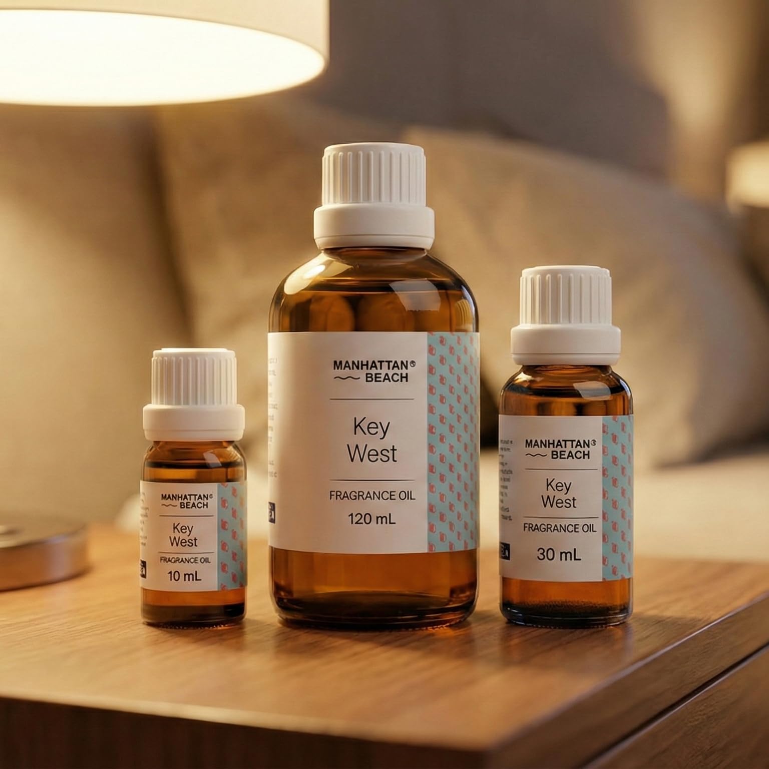 Three bottles of Manhattan Beach Key West fragrance oil on a wooden surface with a blurred background.